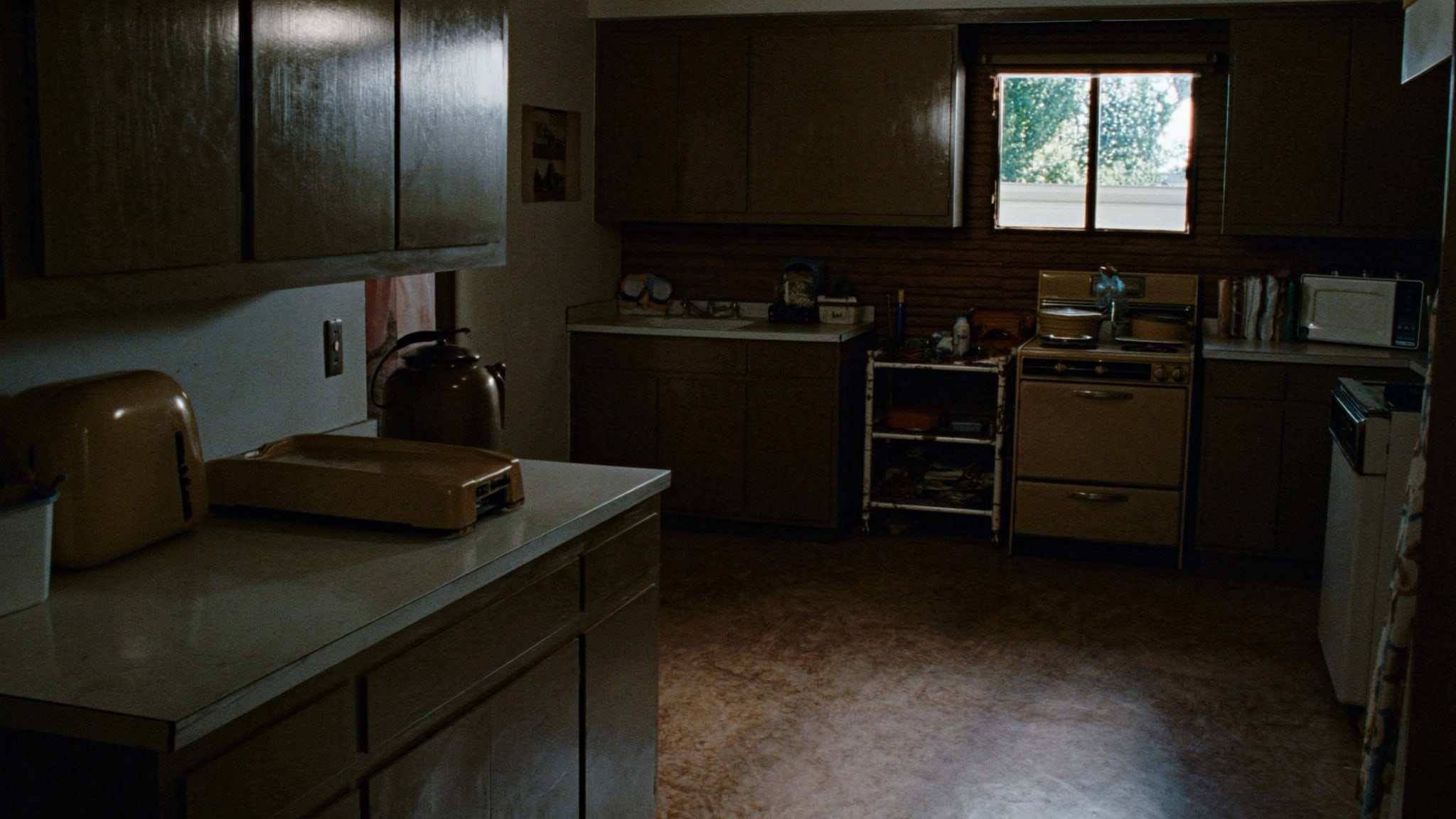 Dated 1970s kitchen with wood cabinets and worn flooring