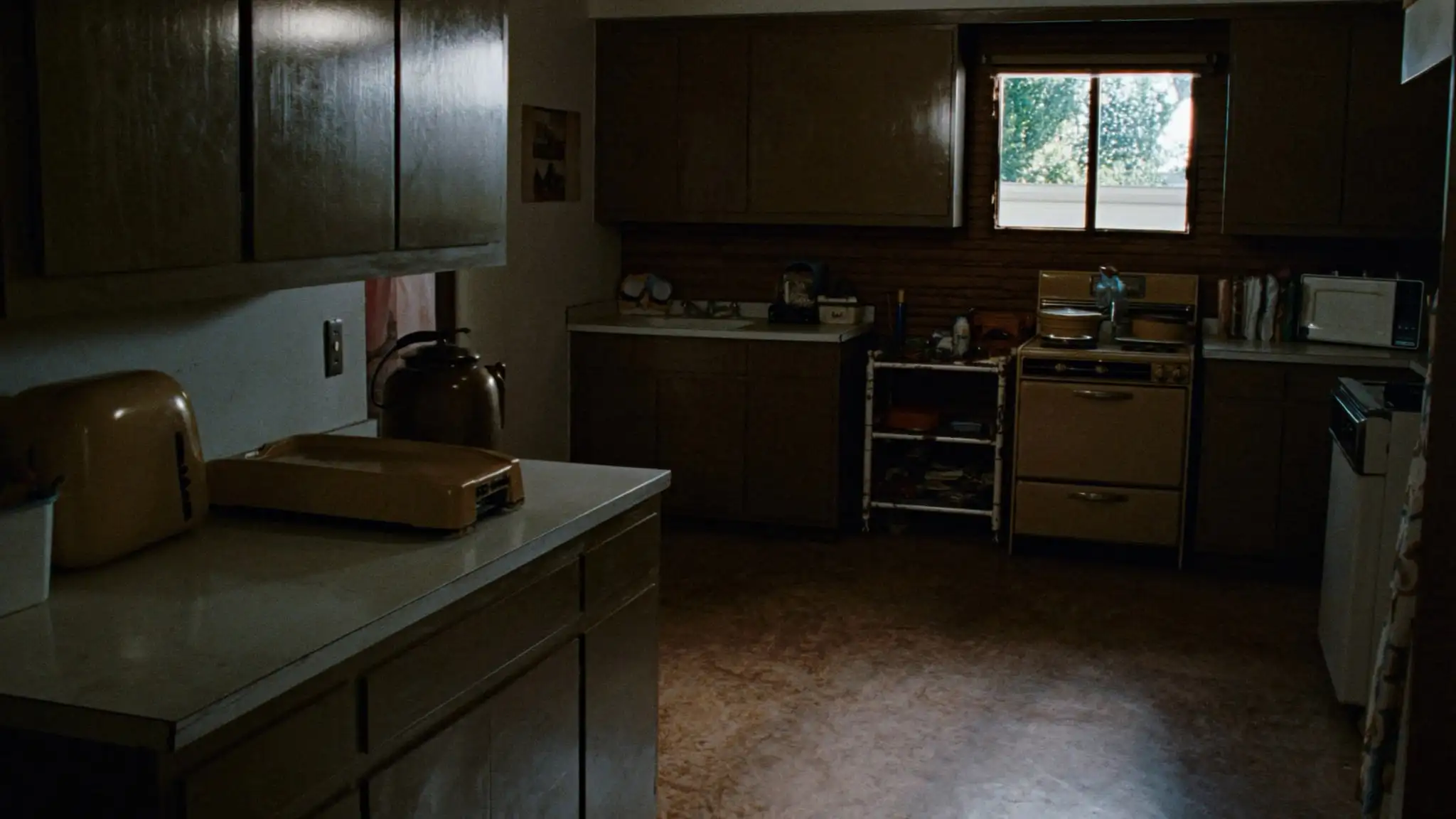 Dated 1970s kitchen with wood cabinets and worn flooring