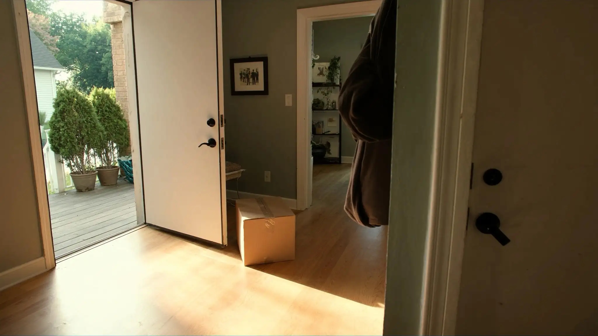 Front hallway of an older home with the door open to the porch and a packed box