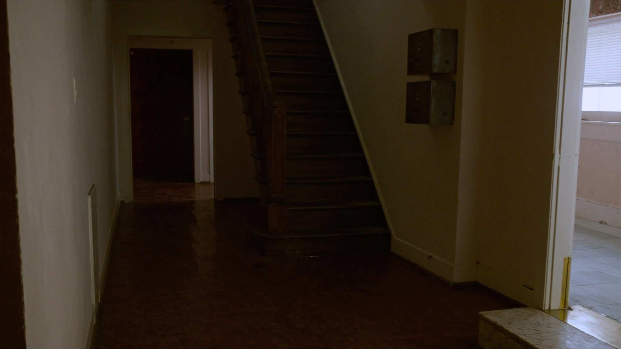 Entry hallway of an older two-flat with mailboxes and a staircase