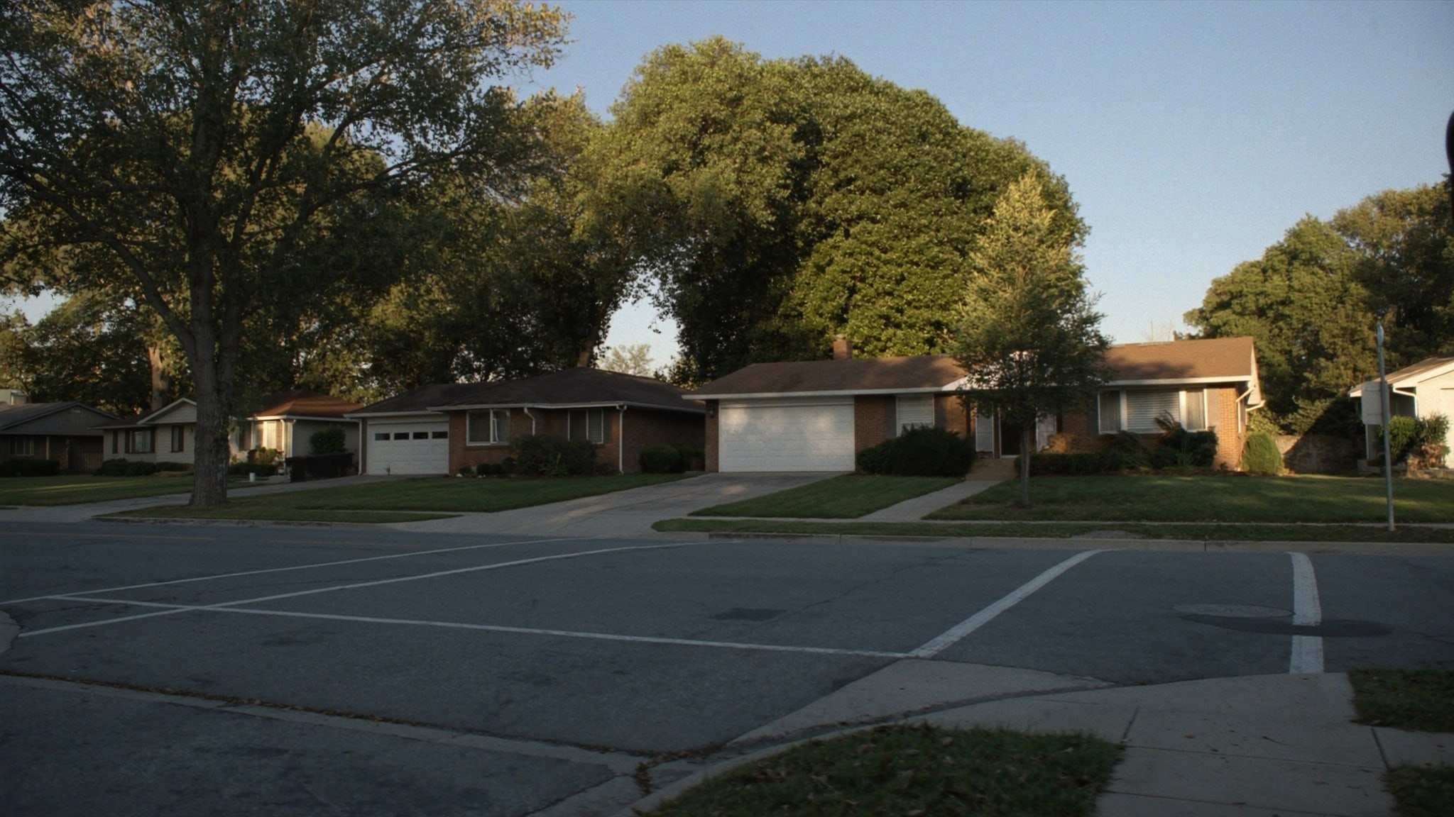 Brick ranch homes with attached garages on a quiet suburban street
