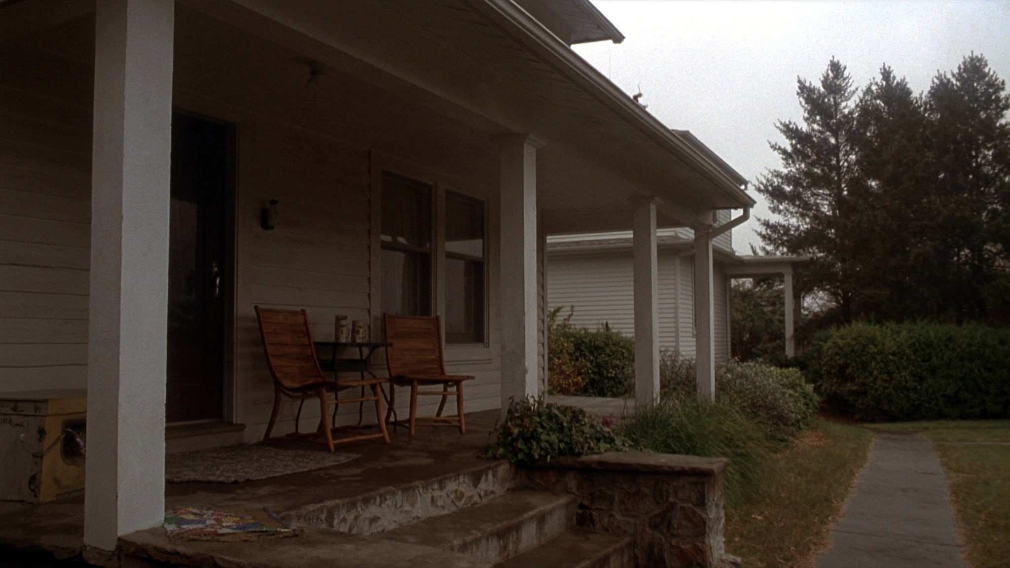Front porch of a two-story house with two chairs